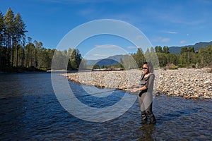 An asian women in waders, enjoying fishing a river in British Columbia, Canada photo