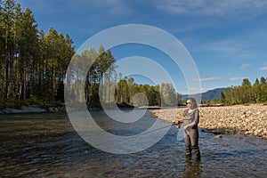 An asian women in waders, fishing a river in British Columbia, Canada