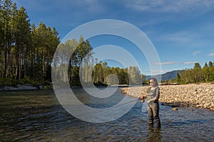 An asian women in waders, fishing a river in British Columbia, Canada photo