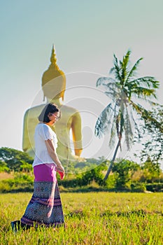 An Asian Women walking and walking meditation the temple in the lawn behind golden Buddha image