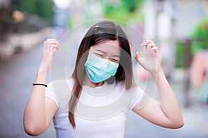 Asian women wearing green medical face mask are depressed due to new lifestyle practices from the emerging coronavirus.