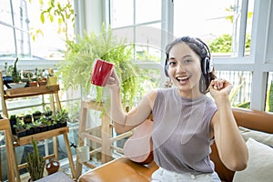 Asian women wearing headphones and using laptop and digital tablet for Listening to music and singing on a relaxing day and