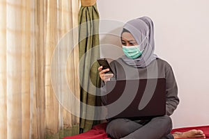 Asian women wearing hijabs wearing masks are working from home