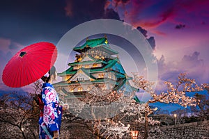 Asian women wearing kimonos See cherry blossoms in the evening around the Osaka Castle, Japan