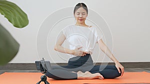 Asian women wearing sportswear and training online course yoga on smartphone in living room at home. wellness concept.