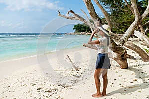 Asian women whit hat looking out over the ocean of La Digue Seychelles Islands