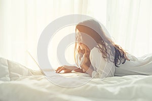 Asian women on white bed.  Women working on laptop in morning relax mood in winter season.