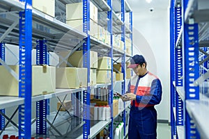 Asian worker on a automotive spare parts warehouse checking products