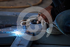 Asian worker making sparks while welding steel