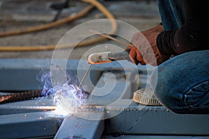 Asian worker making sparks while welding steel