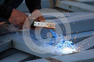 Asian worker making sparks while welding steel