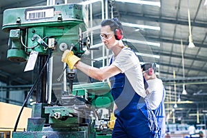 Asian worker in production factory drilling