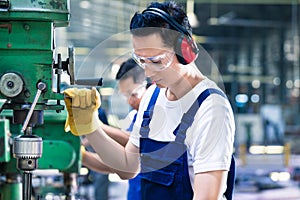 Asian worker in production factory drilling