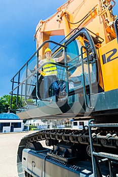 Asian worker on shovel excavator construction site