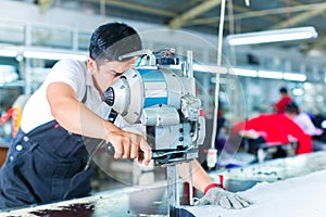 Asian worker using a machine in a factory