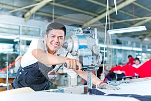 Asian worker using a machine in a factory photo