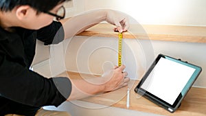 Asian worker using tape measure on ladder