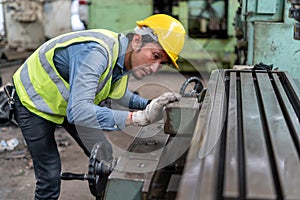 asian worker wearing helmet working with machine in factory . industrial engineer operating lathe machine