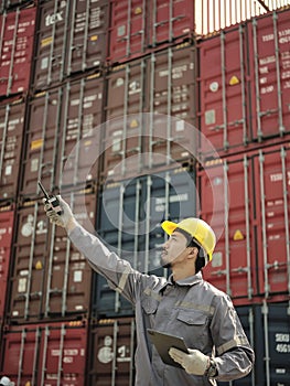 Asian worker wearing safety helmet and using walkie talkie
