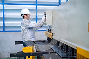 Asian worker wearing a safety suit and setting Hydraulic Press Break Machine and Prepared Sheet Metal Shearing in industrial