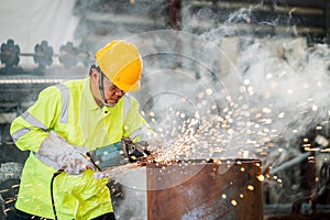 Asian worker is working electric wheel grinding on steel structure in factory