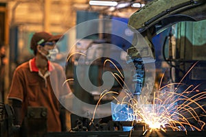 Asian worker working in old chinese factory in robot auto welding machine section