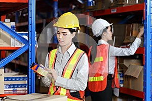 Asian workers are packing product in cardboard box while working in warehouse with full safety equipment for distribution