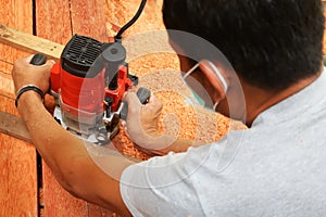 Workers using electric routering to cut on the wood and sawdust