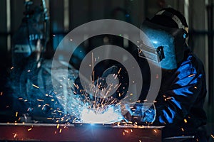 Asian workers wearing industrial uniforms and welded iron mask at steel welding plants. heavy industrial worker inside factory