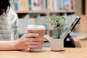 Asian working women used coffee paper cup and working in co working space