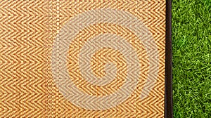 Asian woven wood or rattan mat on green grass texture background