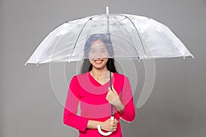 Asian young adult 20s Woman with long black straight hair wear pink dress. Female hold transparent umbrella, feeling emotion
