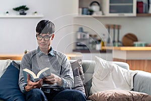 Asian young adult man reading fiction book at home