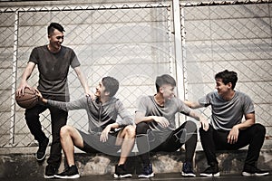 Asian young adults resting relaxing on outdoor basketball court