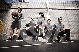 Asian young adults resting relaxing on outdoor basketball court