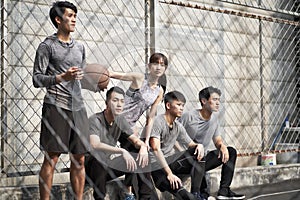 Asian young adults resting relaxing on outdoor basketball court