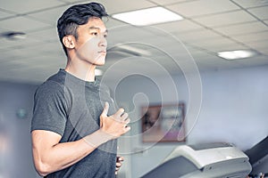 Asian young atheletic man in sportswear running on treadmill at gym