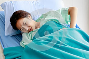 An asian young beautiful female patient has stomachache or period pain and feel unwell while lying on bed in hospital. Medical