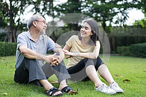 Asian young beautiful girl daughter take care of mature senior elderly grandfather in garden. Attractive woman and older man