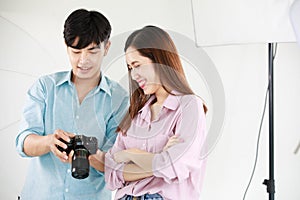 Asian young beautiful long brown hair female model and handsome male photographer holding full frame dslr camera in hands stand