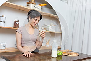 Asian young beautiful woman drinking glass of milk in kitchen at home. health care concept