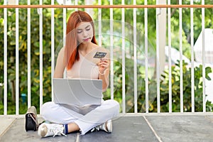 Asian young beautiful woman red hair sitting on floor with laptop computer with holding credit card.