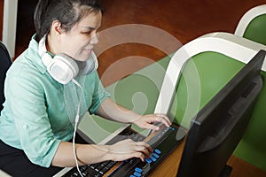 Asian young blind woman with headphone using computer with refreshable braille display or braille terminal a technology device for photo