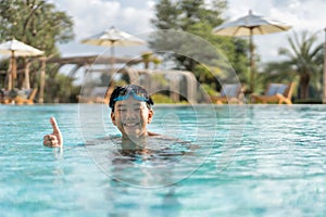 Asian Young Boy Having a good time in swimming pool, He Jumping and Playing a Water in Summer