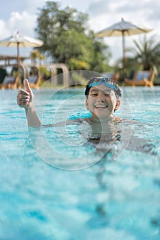 Asian Young Boy Having a good time in swimming pool, He Jumping and Playing a Water in Summer