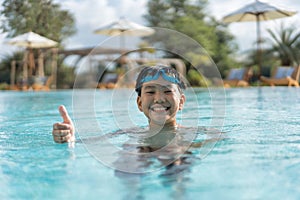 Asian Young Boy Having a good time in swimming pool, He Jumping and Playing a Water in Summer