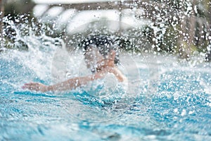 Asian Young Boy Having a good time in swimming pool, He Jumping and Playing a Water in Summer