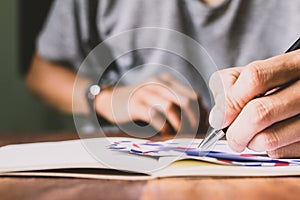 Asian young business man of student holding a pen writing letter on paper at home