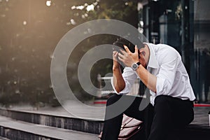 Asian young businessman stress sitting in front office with his hands covering his head against