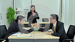 Asian Young businessmen and asian senior businessmen are wrestling with a cheering secretary nearby, the concept of a fight betwee